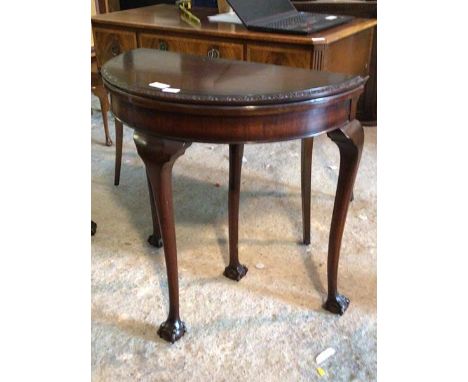 A Chippendale design mahogany demi-lune fold over card table with baize lining and ball and claw supports H75cm, W79cm, D43cm