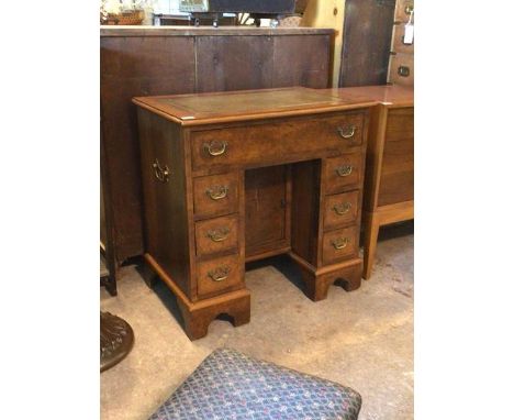 A Quality 20th century figured walnut knee hole desk, the top inset with tooled leather writing surface over one long and six