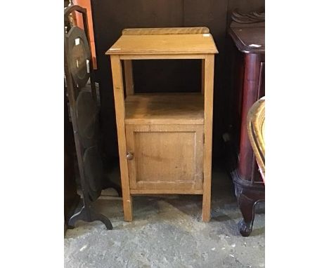 An early 20th century oak bedside cupboard, with raised back over moulded top and open shelf, cupboard to base, raised on sti