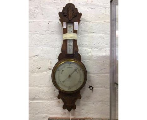 A late Victorian oak aneroid barometer and thermometer in a banjo pattern case with silvered dials H73cm