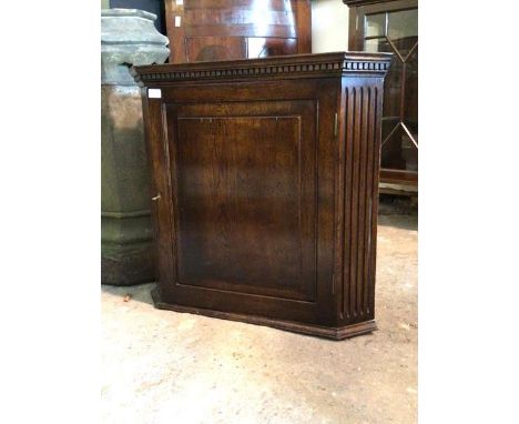An oak wall hanging corner cupboard of 18th century design with dentil cornice and panelled cupboard enclosing a shelf, H71cm