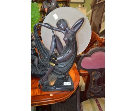 A reproduction table lamp of an Art Deco dancer beneath the full moon