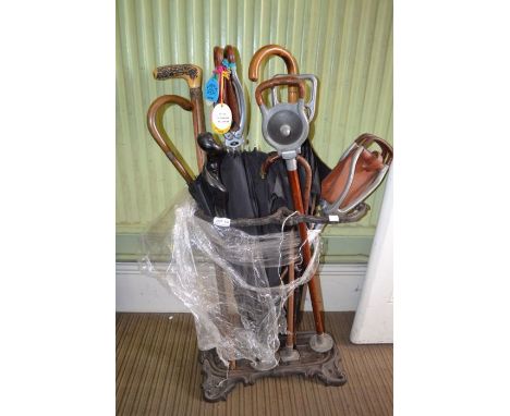 A cast iron stick stand, containing shooting sticks, umbrellas, etc.