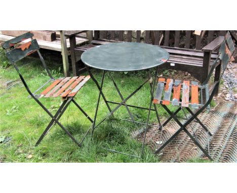 A contemporary weathered green painted light steel three piece folding bistro set together with a pair of cast iron bench end