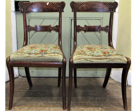 A pair of Regency mahogany dining chairs with hand worked tapestry seats on sabre forelegs 