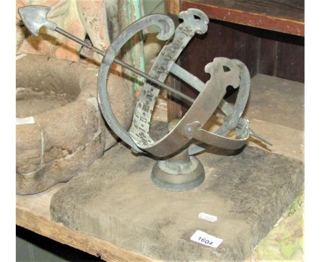 A small weathered Oriary cast metal sun dial with arrow detail and Roman numerals, raised on an associated reclaimed square c