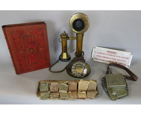 A vintage brass candlestick telephone together with a a further vintage ticket punching machine and tickets, an enamel sign a