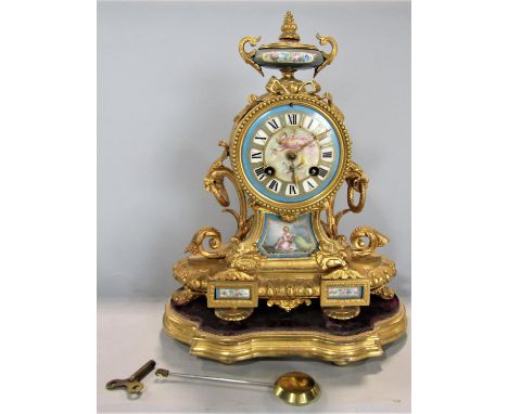 A good French ormolu Rococo style mantle clock, fitted with Sevres style painted enamel panels, two train movement upon a gil