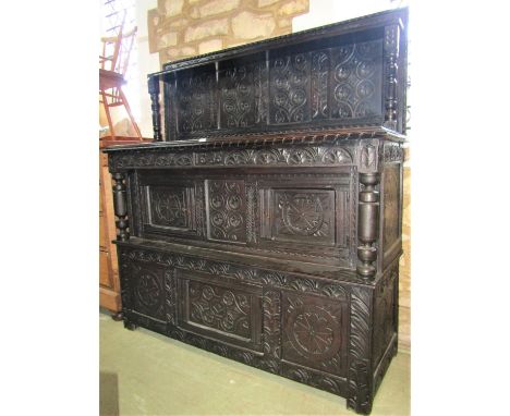 An old English oak buffet enclosed by a number of geometrically carved panels with turned column supports, the raised back in