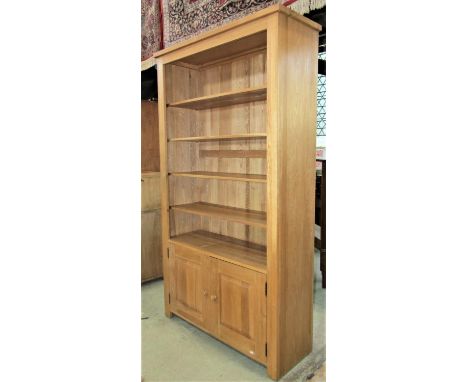 A contemporary good quality light oak freestanding open side cupboard, with four adjustable shelves over a pair of fielded pa