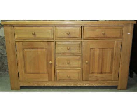 A contemporary light oak dresser fitted with a T shaped arrangement of six drawers flanked by fielded panel doors, 160cm wide