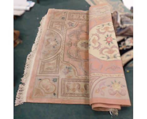 A large late 20thC wool carpet, with geometric panels, acanthus and floral motifs, on a pink ground, with white fringing to e