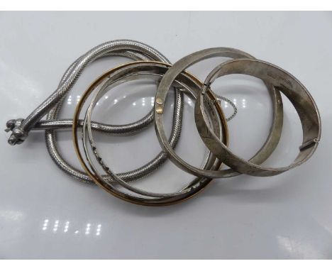A modern silver and bright cut hinged bangle; together with another silver bangle; an Arts &amp; Crafts silver bangle; a roll