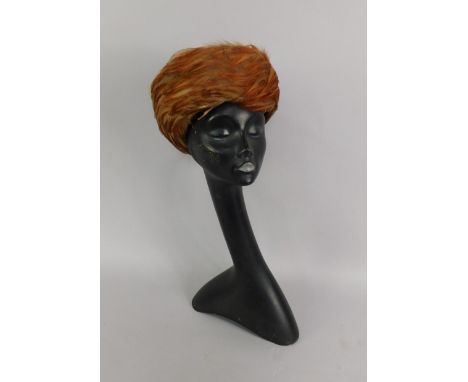 A black stylised female mannequin bust, together with a lady's feather hat, (2).