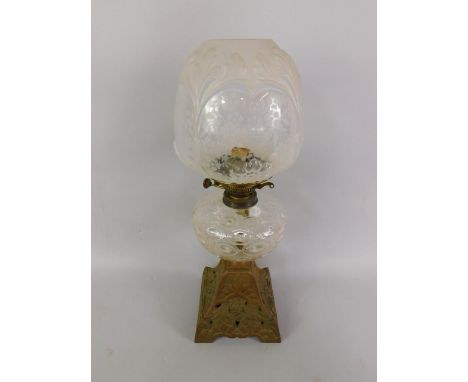 A Duplex late 19thC cast iron oil lamp, cast with cherubs heads and leaves, with a dimpled glass reservoir and frosted, mould