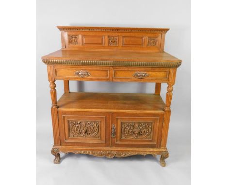 A Victorian oak buffet, with a carved and panelled back, above two frieze drawers, raised on cabriole legs and ball and claw 