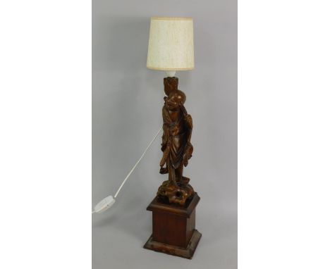 A Chinese carved hardwood figure of a peasant holding a bat, raised on a wooden plinth, converted to a table lamp, 78cm high.