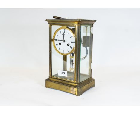 A late 19th/early 20th century French brass four-glass mantle clock, circular white enamel dial supporting a twin train movem