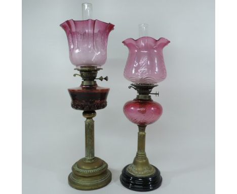 A Victorian brass oil lamp, with a cranberry glass reservoir and frilled glass shade, 64cm tall, together with another, with 