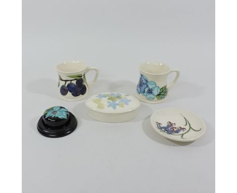A collection of Moorcroft pottery items to include two mugs, 8cm tall, a trinket box, trinket dish and paperweight