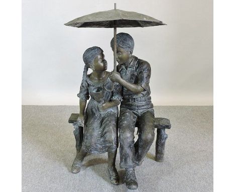 A large modern bronze figure group of two children, seated on a bench holding an umbrella, 103cm tall