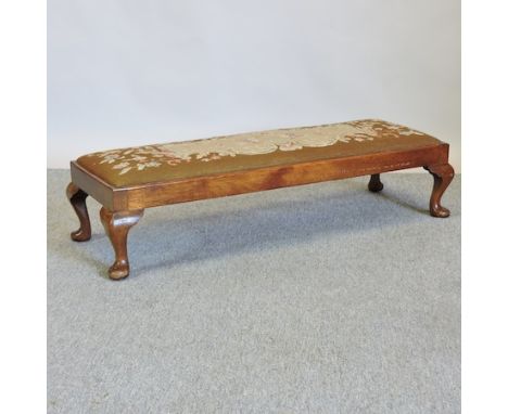 A 1920's walnut and tapestry upholstered Queen Anne style foot stool, 106cm