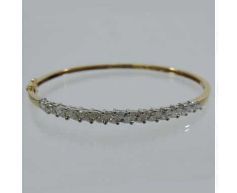 An 18 carat gold diamond set hinged bangle, set with a single row of fifteen marquise cut diamonds 