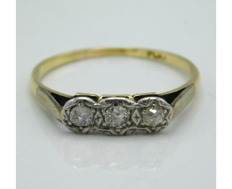 A yellow metal three stone platinum mounted diamond ring, tests electronically as 18ct gold, approx. 0.2ct, size R/S, 2.1g