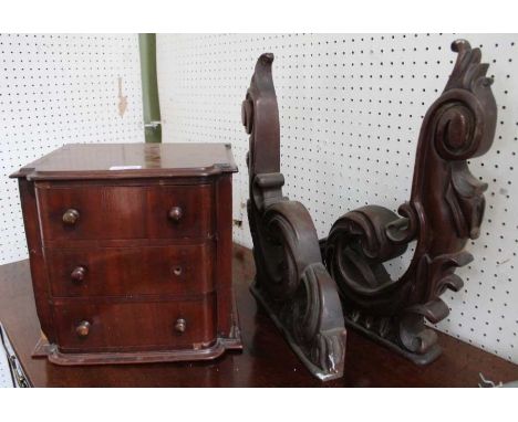 A pair of carved mahogany shelf brackets with a tabletop three drawer chest
