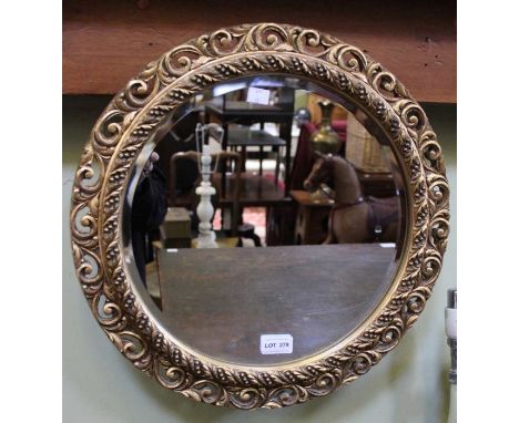 A small circular fancy edged gilt framed wall mirror