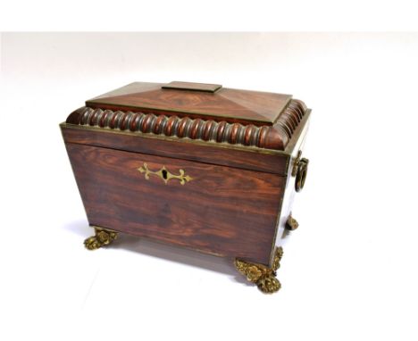 A REGENCY ROSEWOOD SARCOPHAGOS  SHAPED TEA CADDY with gilt metal mounts including ring handles and lion paw bracket feet, the