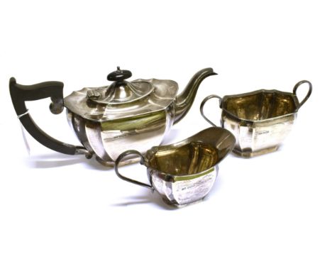 A SILVER SHAPED-OBLONG THREE PIECE TEA SERVICE with scroll handles, the teapot with an ebonised angular handle and finial, ma