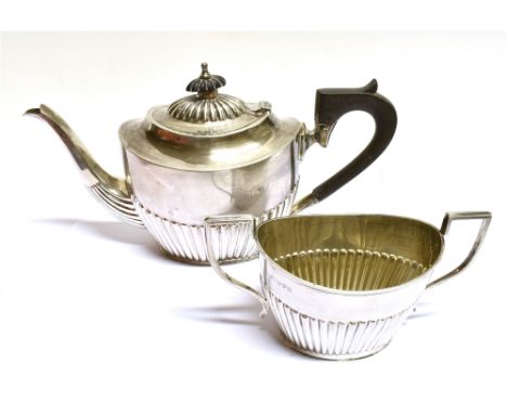 A SILVER OVAL PART-FLUTED TEAPOT AND SUGAR BOWL with angular scroll handles, the teapot with an ebonised handle and finial an