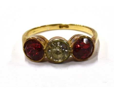 A PASTE THREE STONE RING  the three stone ring centred with a near-colourless round facetted paste between red pastes, all ru