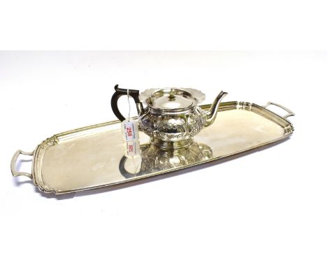 A SILVER MELON FLUTED AND FLORAL EMBOSSED ROUND TEA POT with a shaped everted rim a melon fluted body embossed with stylised 