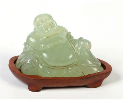 A Chinese carved celadon jade model of a reclining Buddha raised on a hardwood plinth, 7cm.  Condition Report. To be used as 