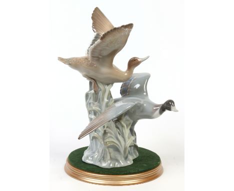 A Lladro figure group formed as a pair of mallard ducks in flight and raised on a giltwood plinth. Printed mark, 35.5cm high.