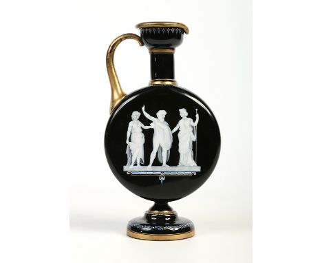 An early 20th century Bohemian opaque black glass pedestal ewer, with gilt and enamel borders and pate sur pate portrait of Z