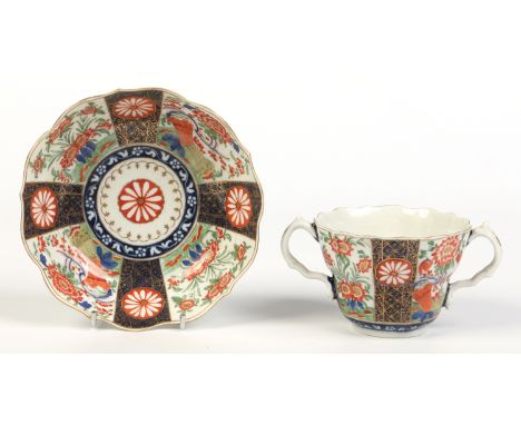 A Worcester chocolate cup and saucer. Decorated in the Imari style with panels of chrysanthemums and banded hedges divided wi