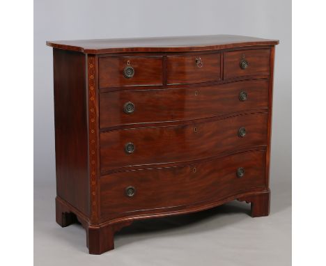 A Georgian mahogany serpentine chest of three over three drawers. With canted corners having marquetry inlay and raised on br