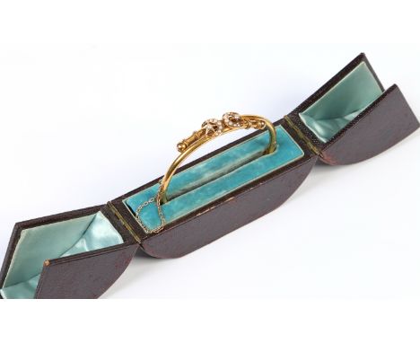 A cased Victorian yellow metal crossover bangle with a pair of crescent moon and star motifs set with seed pearls. Internal m