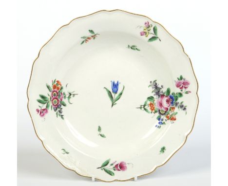 A Worcester plate with scalloped rim edged in gilt and painted in coloured enamels with scattered sprigs. C1770, 22cm wide.  