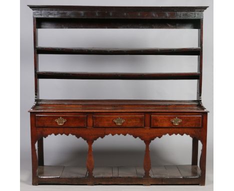 A George II oak three drawer kitchen dresser of small proportions. With three tier delft rack and raised on flat baluster sup