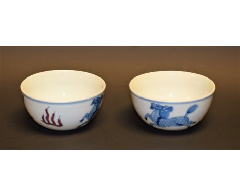 A pair of Chinese porcelain circular tea bowls, painted with longma in underglaze blue and flanked by stylized flames painted