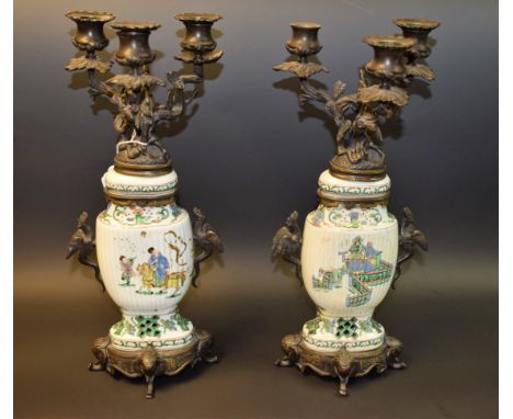 A pair of Chinese bronze and porcelain three light candleabra, with detachable nozzles and branch stems, vase and cover colum