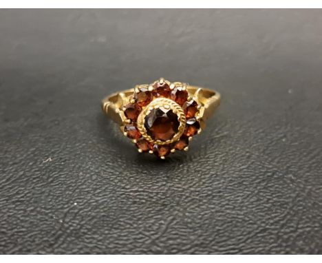 GARNET CLUSTER RINGthe central round cut garnet approximately 0.75cts in further ten garnet surround, on unmarked gold shank,