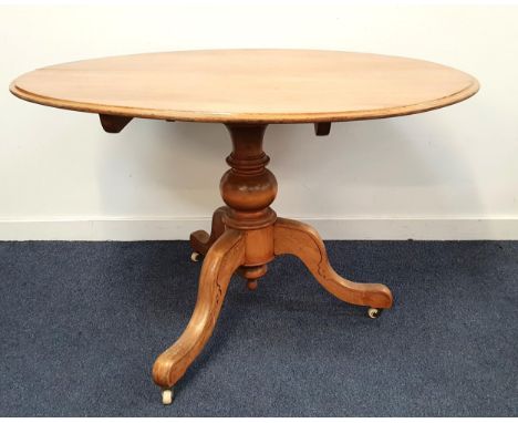 VICTORIAN OVAL MAHOGANY BREAKFAST TABLEwith tilt top and raised on pedestal support with three outswept legs on ceramic casto