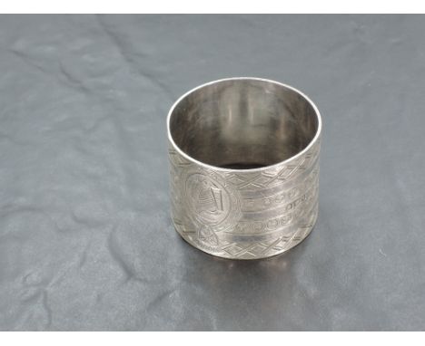 A large Edwardian silver napkin ring, of circular form with repeating geometric decoration centred with an engraved cartouche
