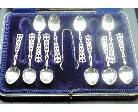 An incomplete cased set of ten silver teaspoons and sugar tongs with pierced Welsh love spoon type decoration to the handles,