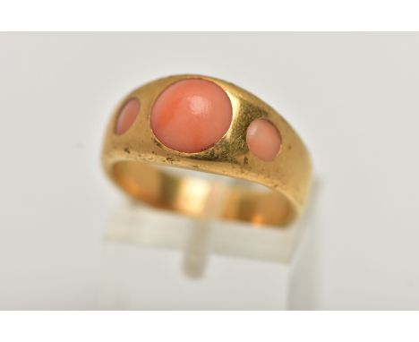 A YELLOW METAL CORAL RING, designed with three circular cut coral cabochon inlayed to a yellow metal tapering band, stamped 1